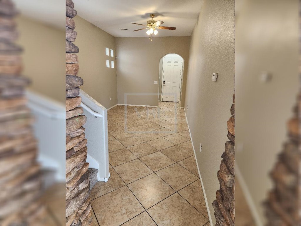 A hallway with a tiled floor and a ceiling fan.