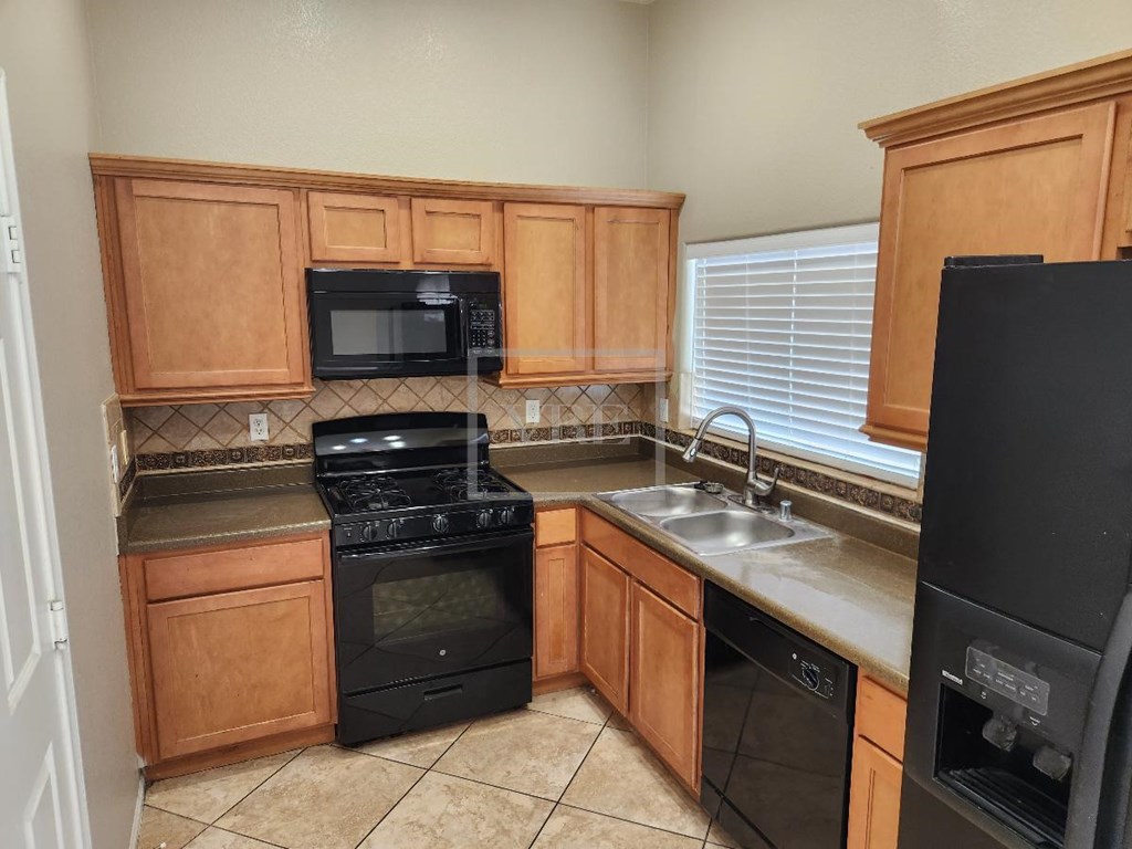A kitchen with wooden cabinets and black appliances.