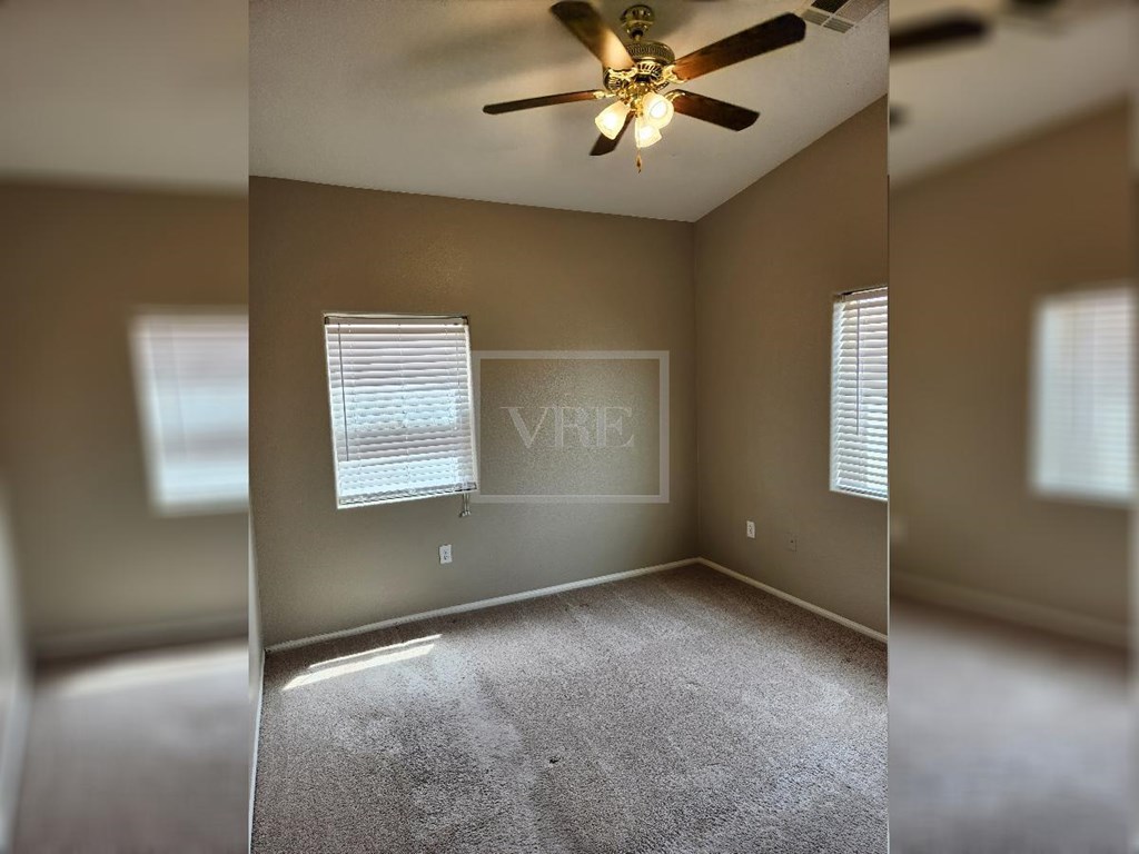 A room with a carpeted floor and a ceiling fan.