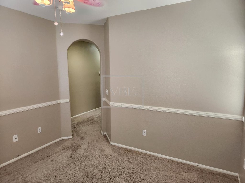A room with a carpeted floor and a doorway leading to another room.