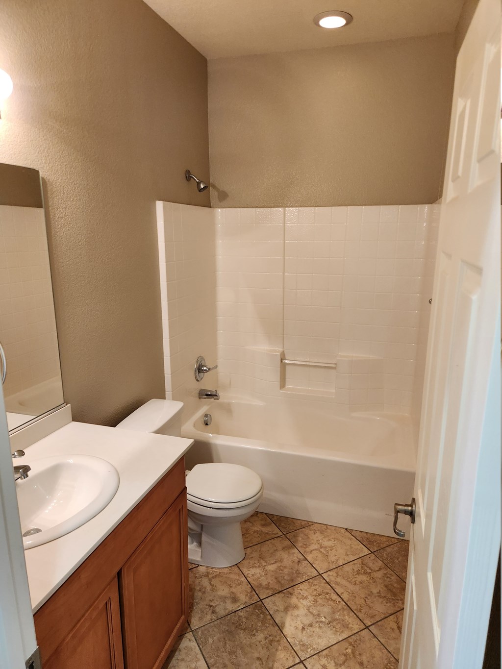 A white toilet is in a bathroom with a white tub and sink.