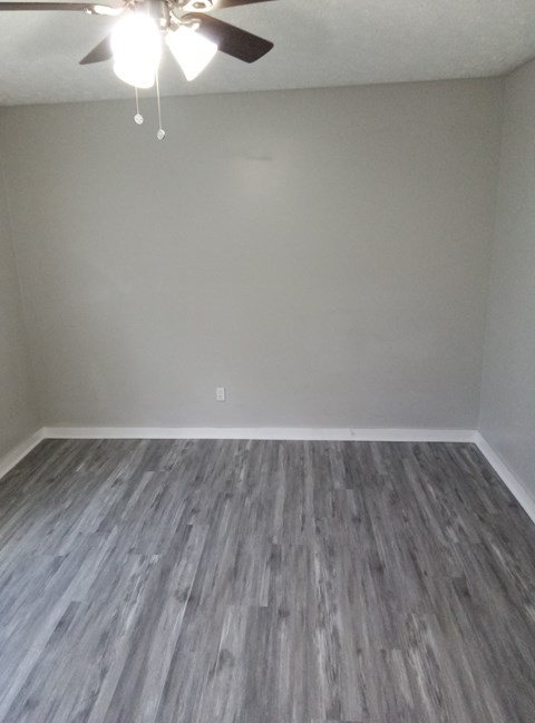 an empty room with vinyl flooring and a ceiling fan