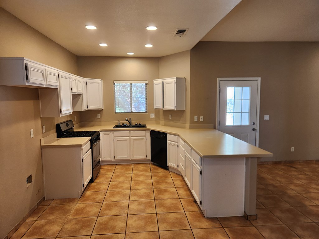 an empty kitchen with white cabinets and a counter top