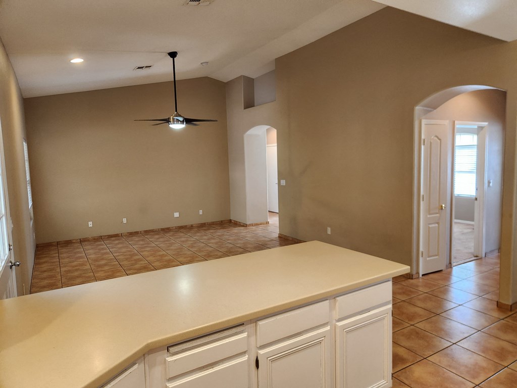 an empty kitchen with an island and a ceiling fan