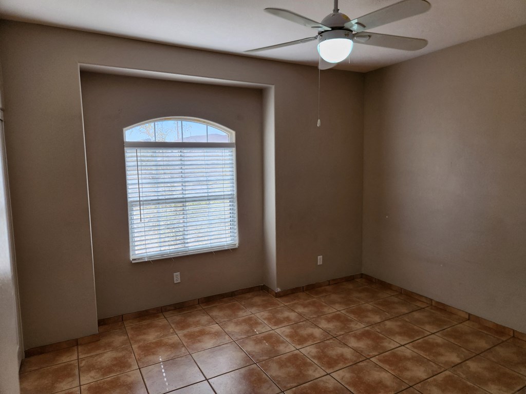 an empty living room with a ceiling fan and a window
