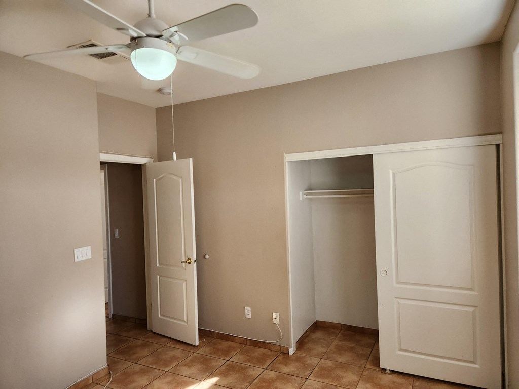 an empty room with two doors and a ceiling fan