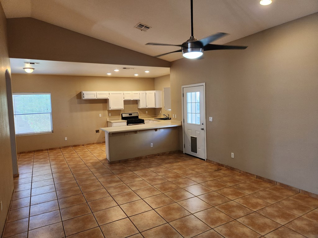 an empty kitchen with a ceiling fan in the middle