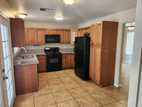 A kitchen with black appliances and wooden cabinets.