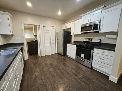 A kitchen with white cabinets and black countertops.