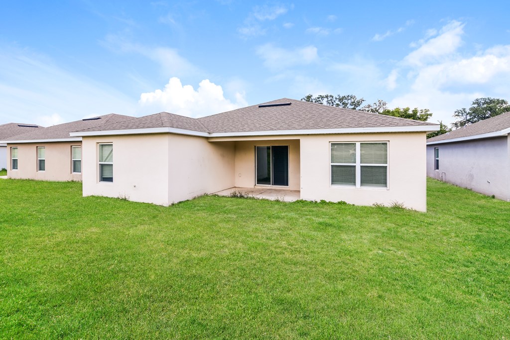 A house with a brown roof and a green lawn in front.