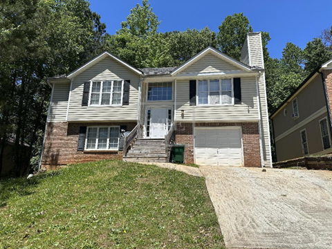 a white and brick house on a hill with a driveway