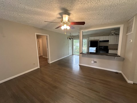an empty living room and kitchen with a ceiling fan