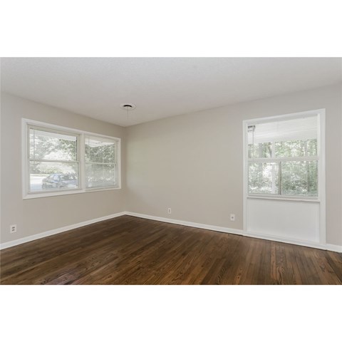A room with wooden floors and two windows.
