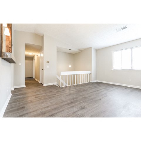 an empty living room with wood floors and a staircase