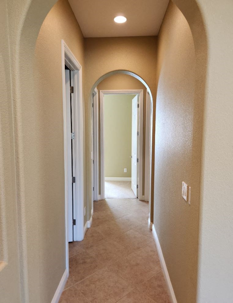 a hallway with an arched door way and a carpeted floor