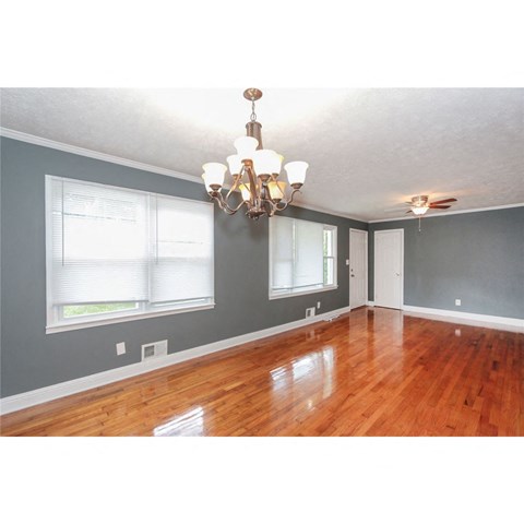 an empty living room with wood floors and a chandelier