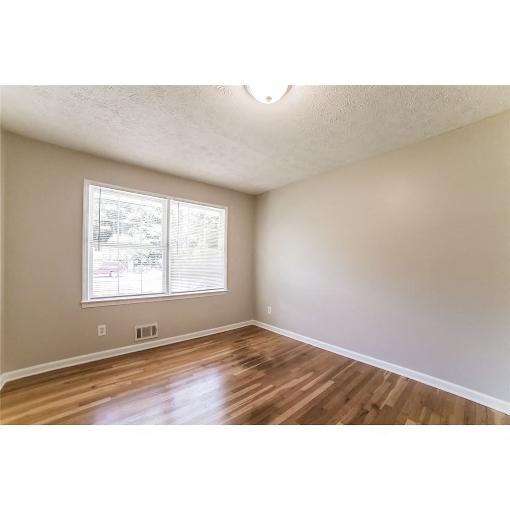 an empty living room with wood floors and a window