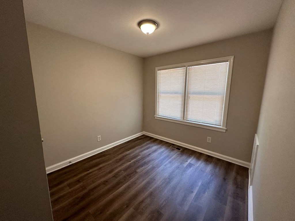 an empty living room with hardwood floors and a window