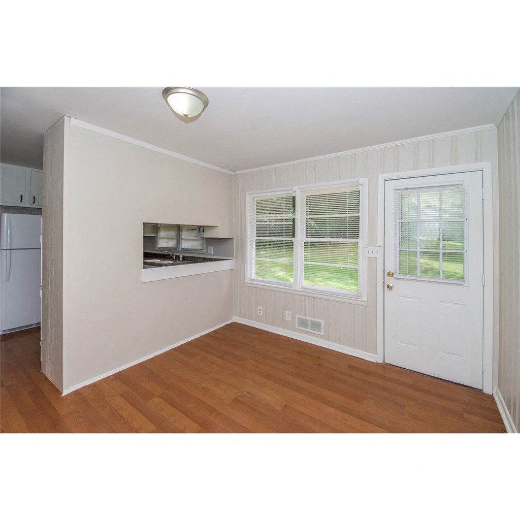 an empty living room with a white door and a window