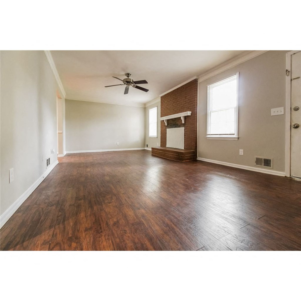 an empty living room with wood floors and a ceiling fan