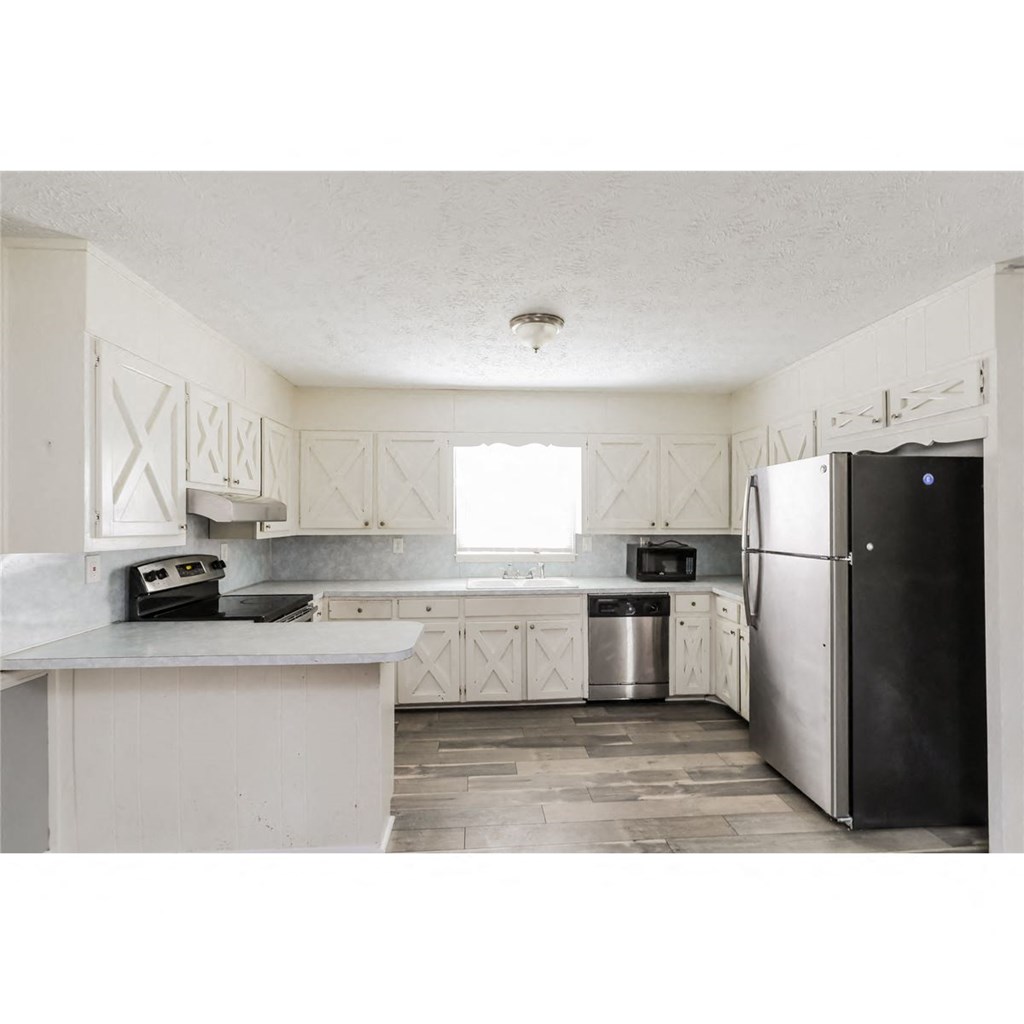 a kitchen with white cabinets and a black refrigerator