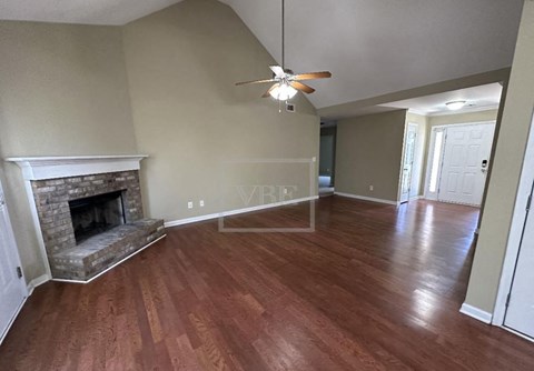 A living room with a fireplace and wood flooring.