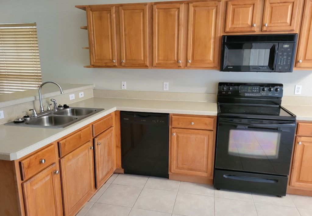 A black oven sits in a kitchen with wooden cabinets.