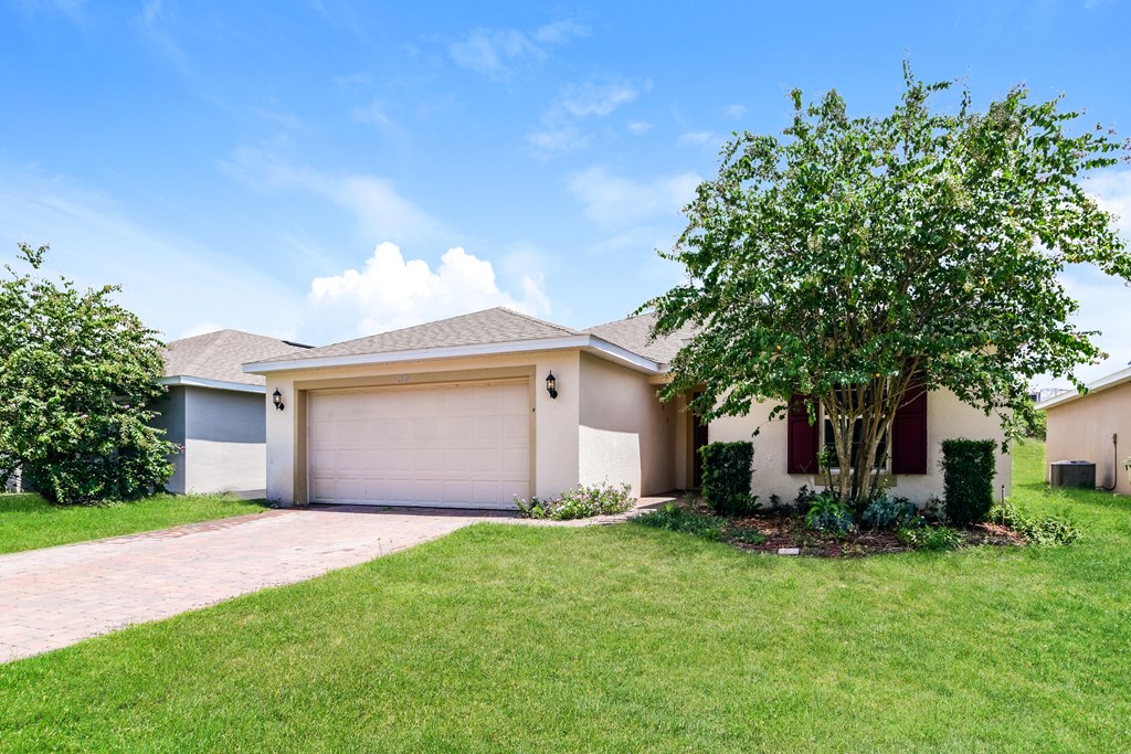 A house with a garage and a tree in front.