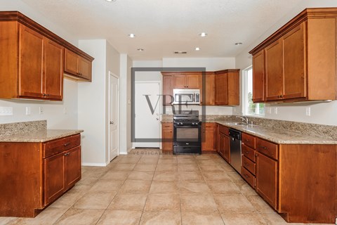A kitchen with brown cabinets and a tiled floor.