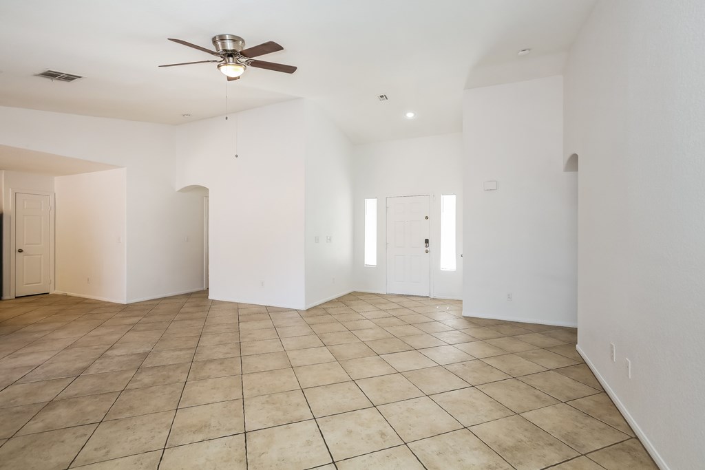 A spacious room with a ceiling fan and tiled flooring.