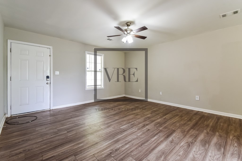 A room with wooden flooring and a ceiling fan.