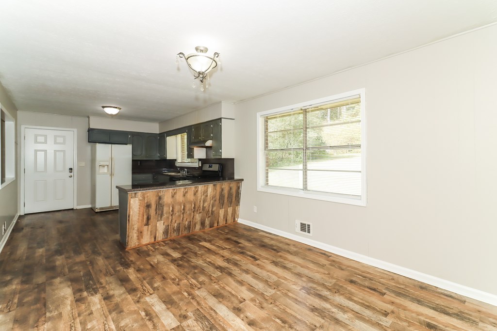 A room with a wooden floor and a window with blinds.