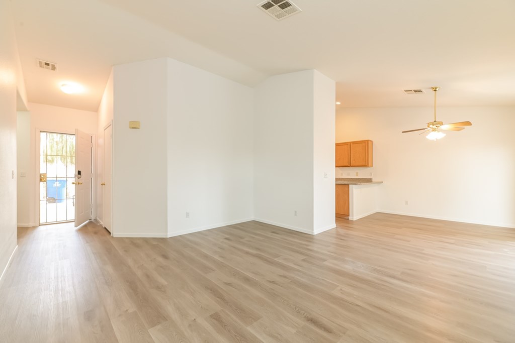 A spacious room with wooden flooring and white walls.