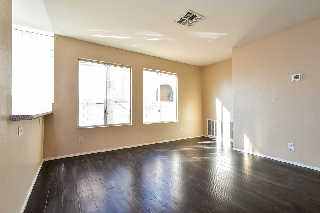 A large empty room with wooden floors and windows.