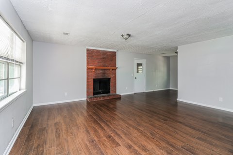 A room with a fireplace and wood flooring.
