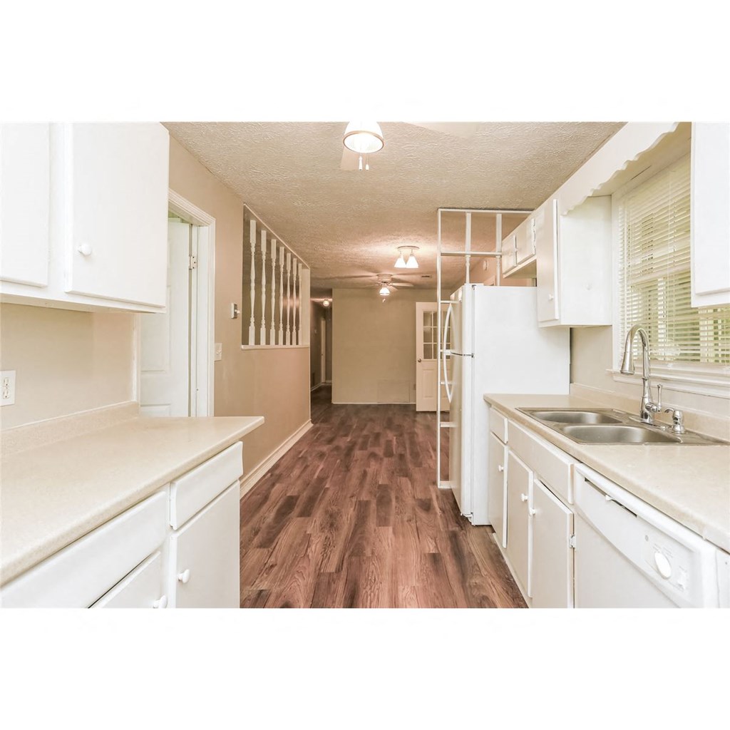 a kitchen with white cabinets and a sink and a refrigerator
