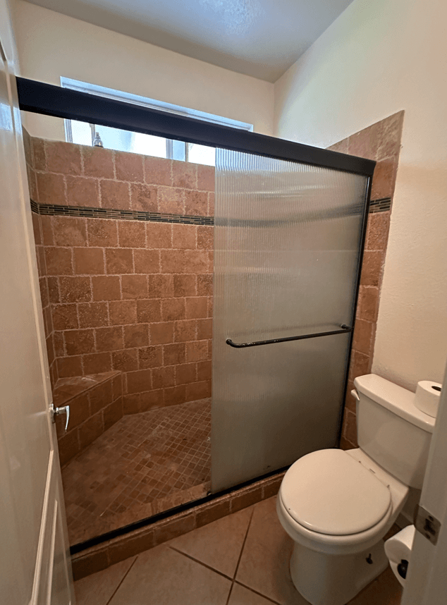 a bathroom with a toilet and a shower with a glass door