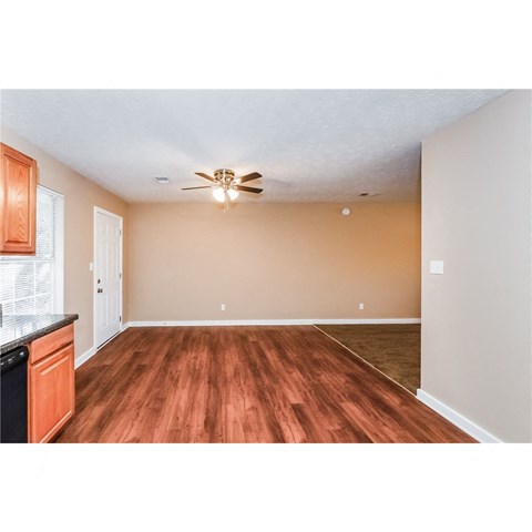 an empty living room and kitchen with a ceiling fan