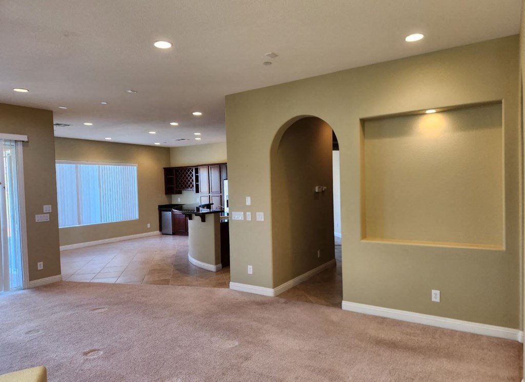 a empty living room with an arched doorway and a carpeted floor