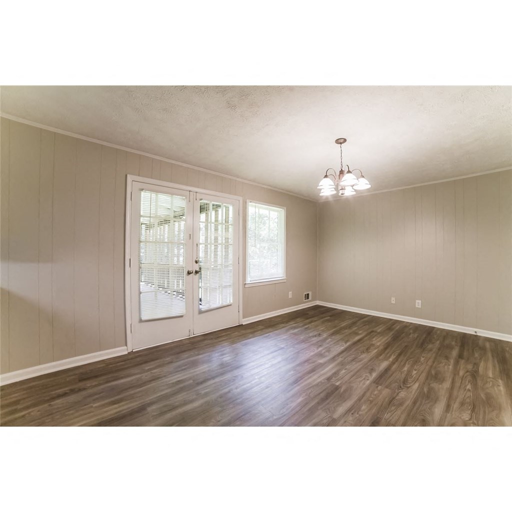 an empty living room with wood floors and a door