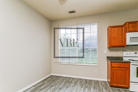 A kitchen with wooden cabinets and a window with blinds.