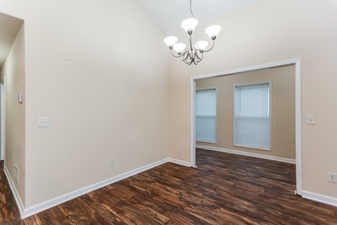 A room with wood flooring and a chandelier.