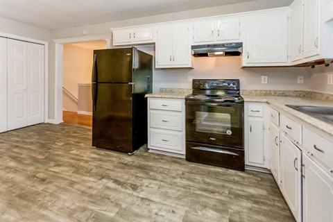 A kitchen with a black refrigerator and white cabinets.