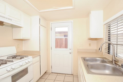 A kitchen with white cabinets and a stove top oven.