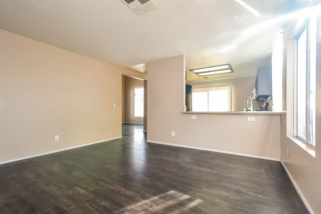 A spacious room with wooden floors and a large window.