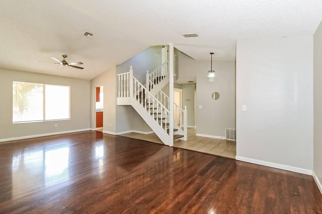 A room with a wooden floor and a staircase.