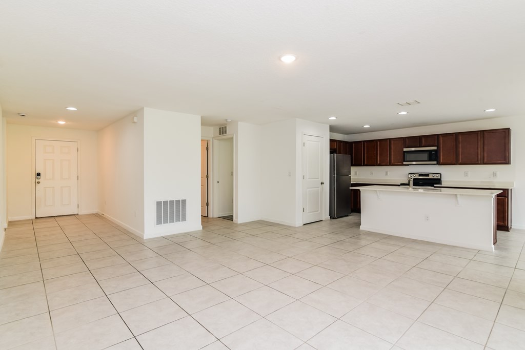 A spacious kitchen with white tiled floors and a white island.