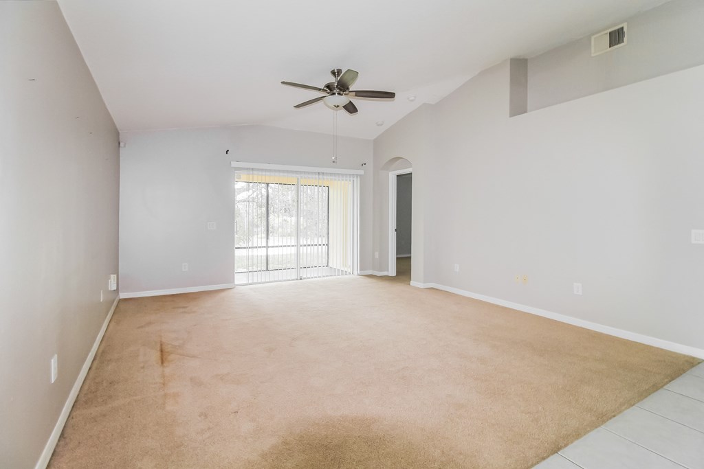 A spacious room with a ceiling fan and a sliding glass door.