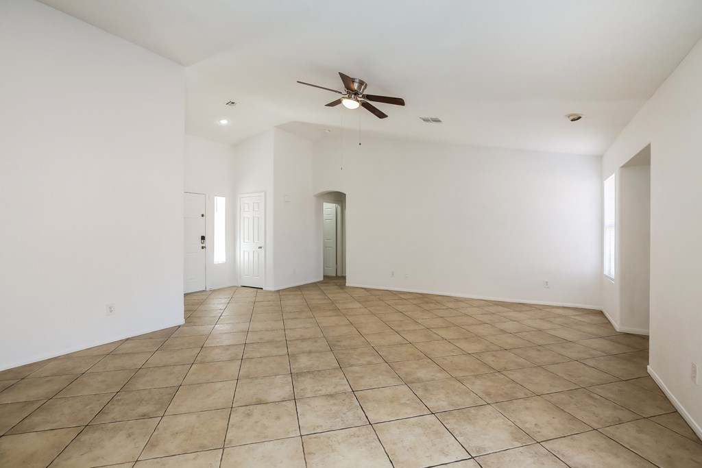 A spacious room with a ceiling fan and tile flooring.