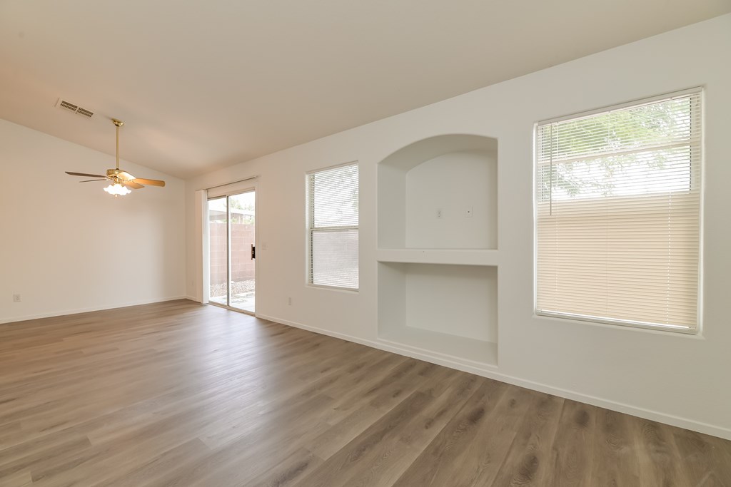 A room with a ceiling fan and wooden flooring.